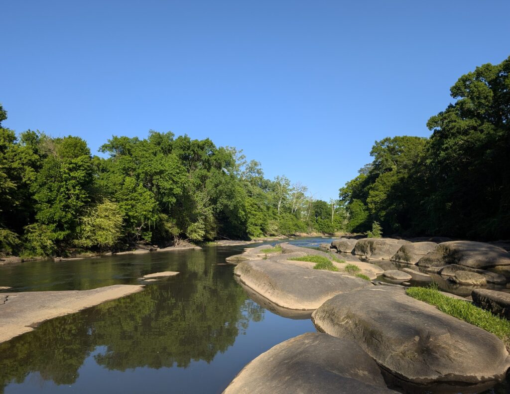 View of the Neuse River showing rocky ledges and some vegetation.